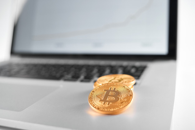sharp-focus-golden-bitcoins-placed-silver-laptop-with-blurred-financial-chart-its-screen_7502-1381